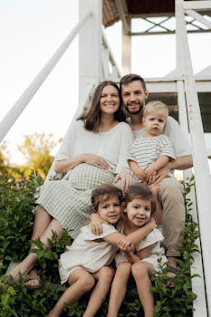A joyful family with three children sitting on outdoor steps, basking in a warm summer day.