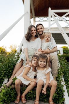 Family of five sitting on stairs, enjoying a sunny day outdoors.