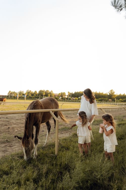 Free A mother and two children interacting with a horse outdoors on a peaceful day. Stock Photo