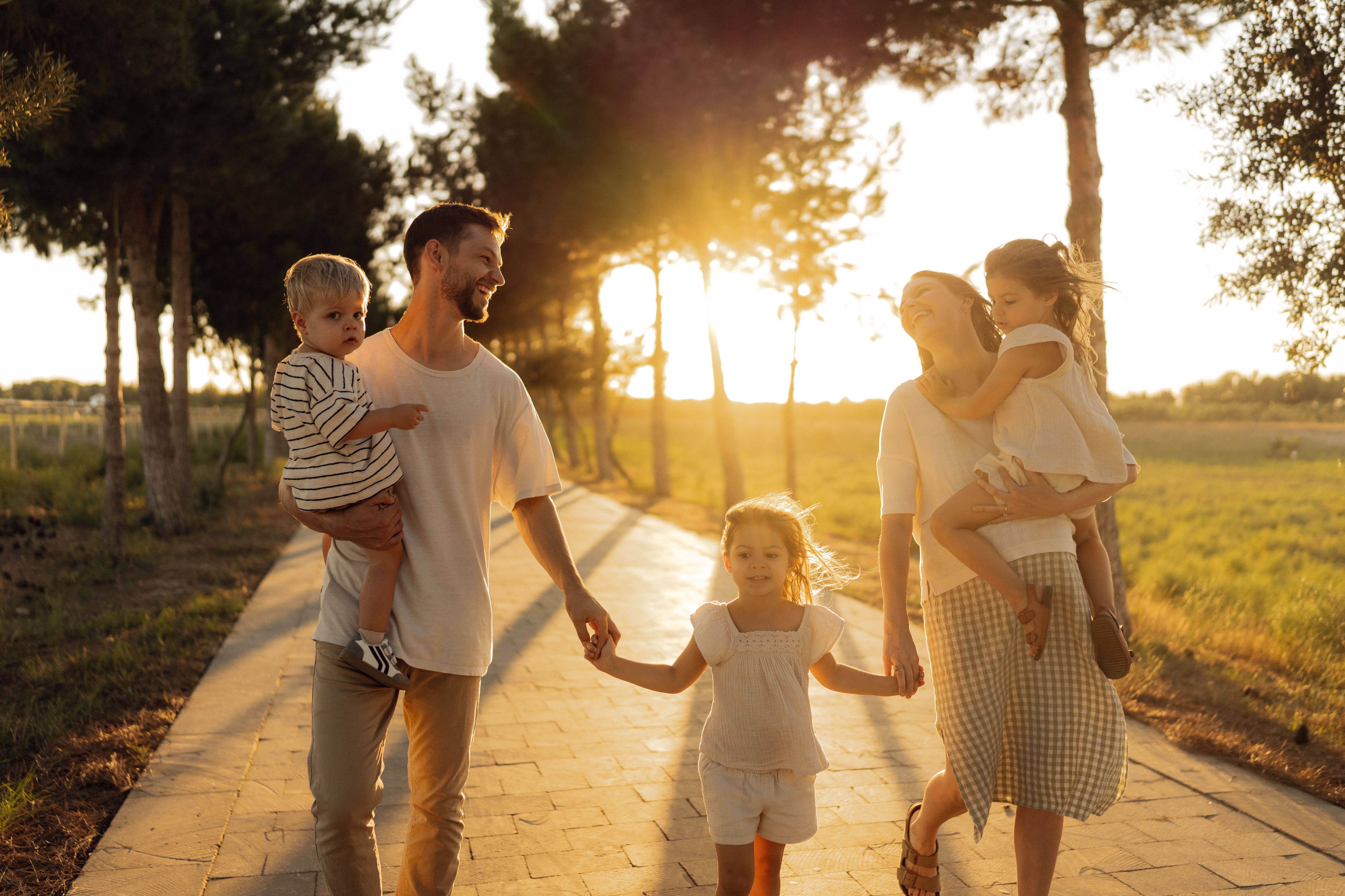 Happy Family Walking on Sunlit Path at Sunset · Free Stock Photo