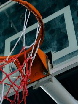 Detailed view of a basketball hoop and net outdoors, highlighting sports theme.