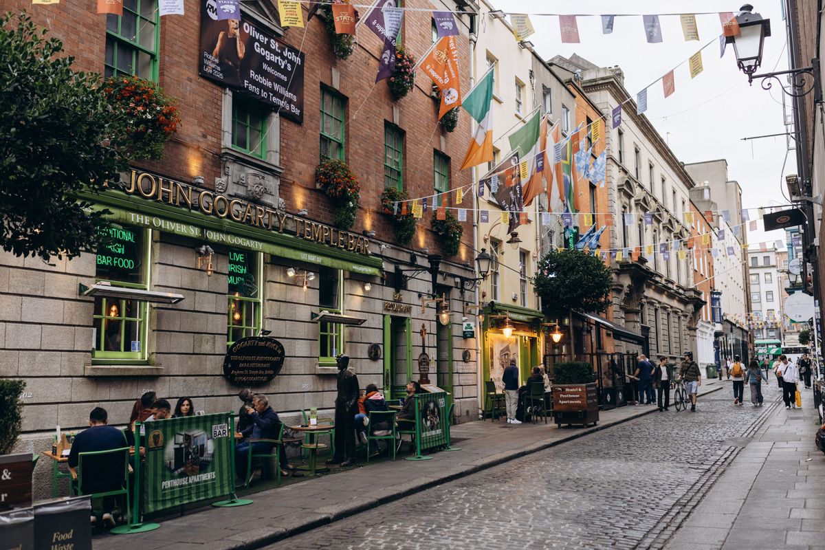 Stradă din cartierul Temple Bar din Dublin, cu fațade colorate de pub și steaguri irlandeze