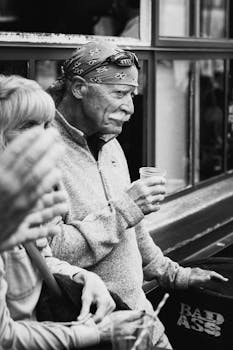 Black and white candid shot of a senior man enjoying a drink outdoors in Dublin.
