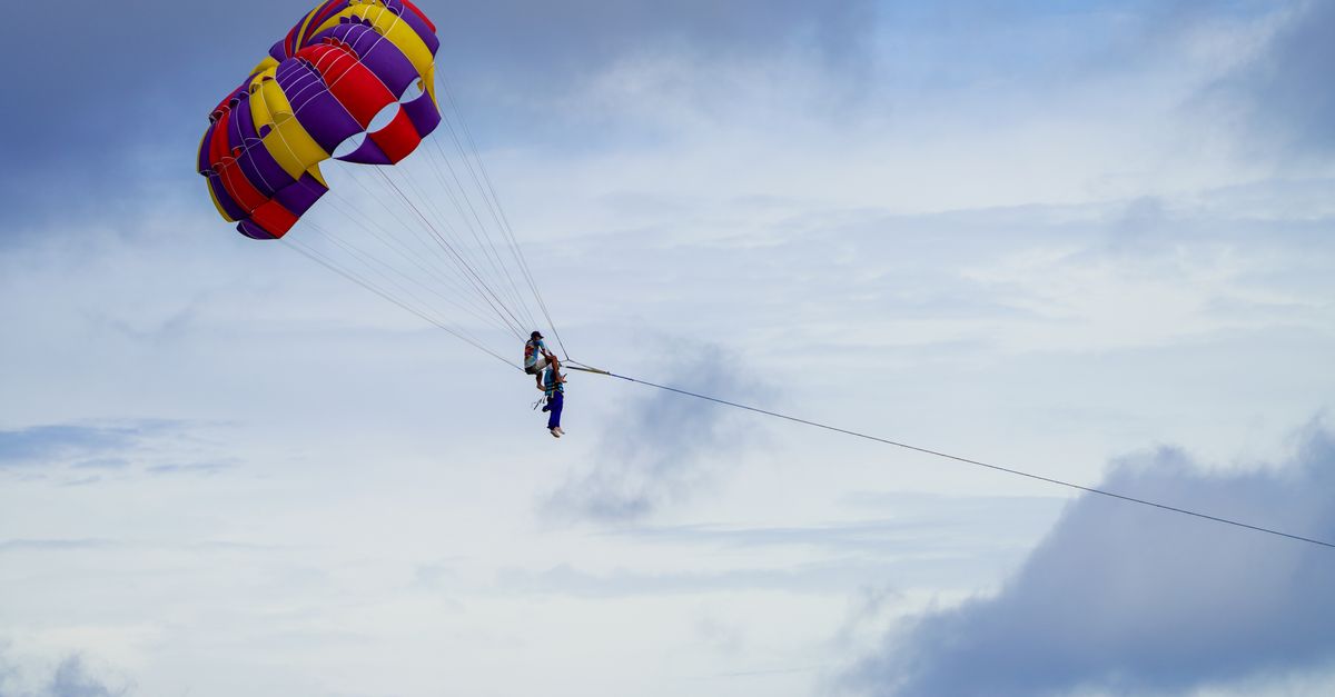 Experience thrilling parasailing over Phuket's stunning beaches with vibrant parachutes against clou