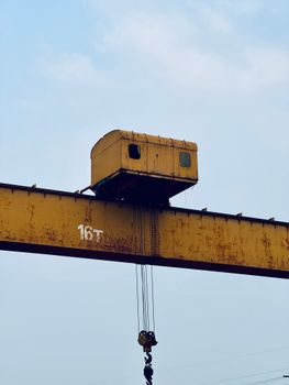Rusty industrial crane with 16T marking against a clear blue sky.