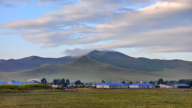Idyllic rural landscape with rolling hills under a partly cloudy sky, showcasing serene countryside beauty.