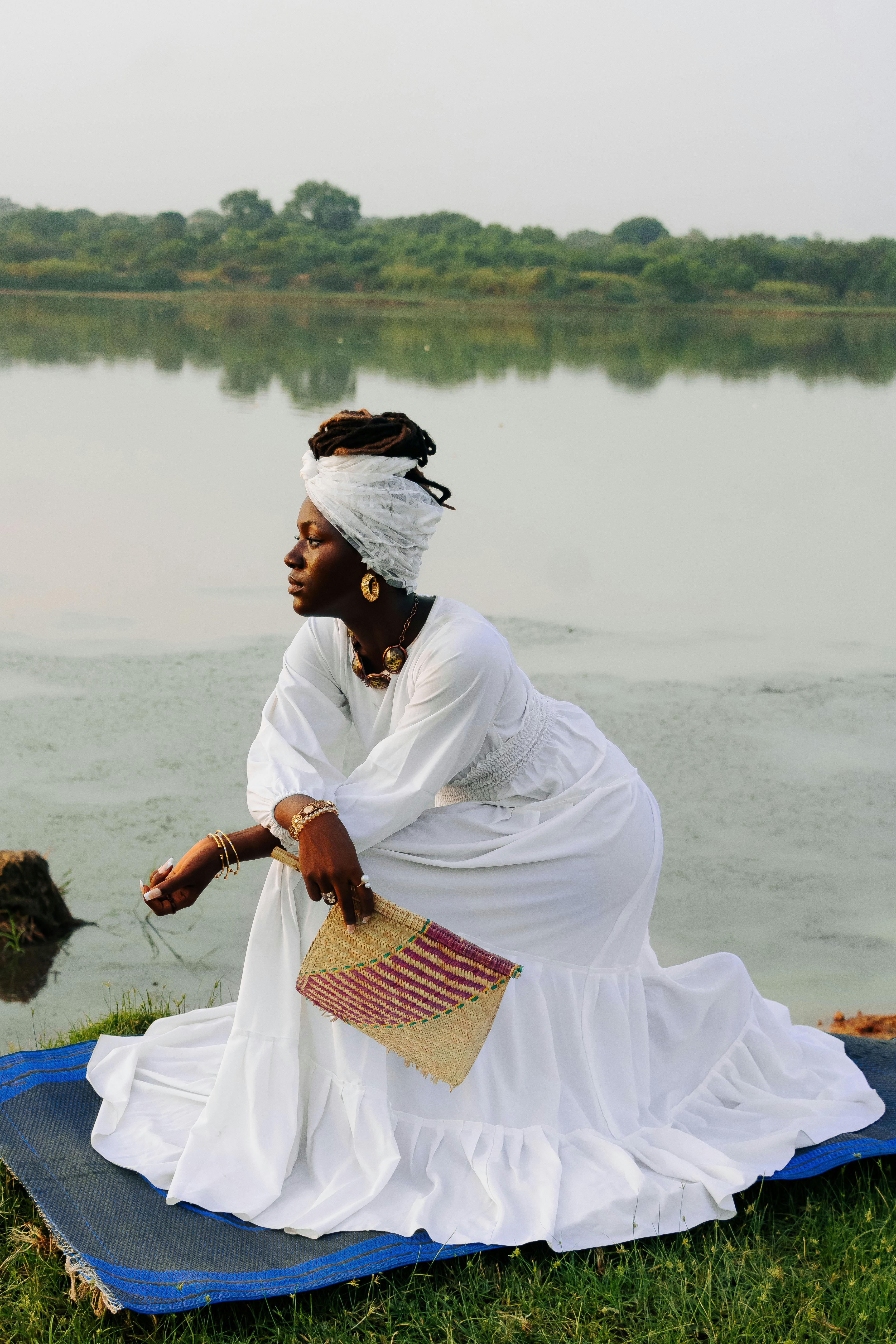 Captivating portrait of a woman in traditional attire by a serene lake in Zaria, Nigeria.