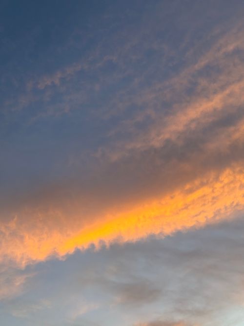 Free A serene twilight sky with dramatic orange clouds against a blue backdrop. Stock Photo