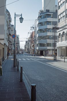 A serene view of a modern urban street surrounded by contemporary architecture and clear skies.