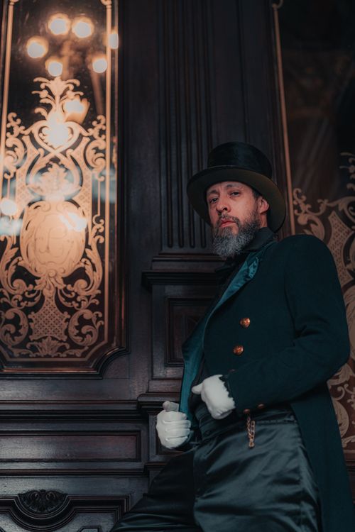 Free A sophisticated man in vintage attire poses against ornate architecture, exuding historical charm. Stock Photo