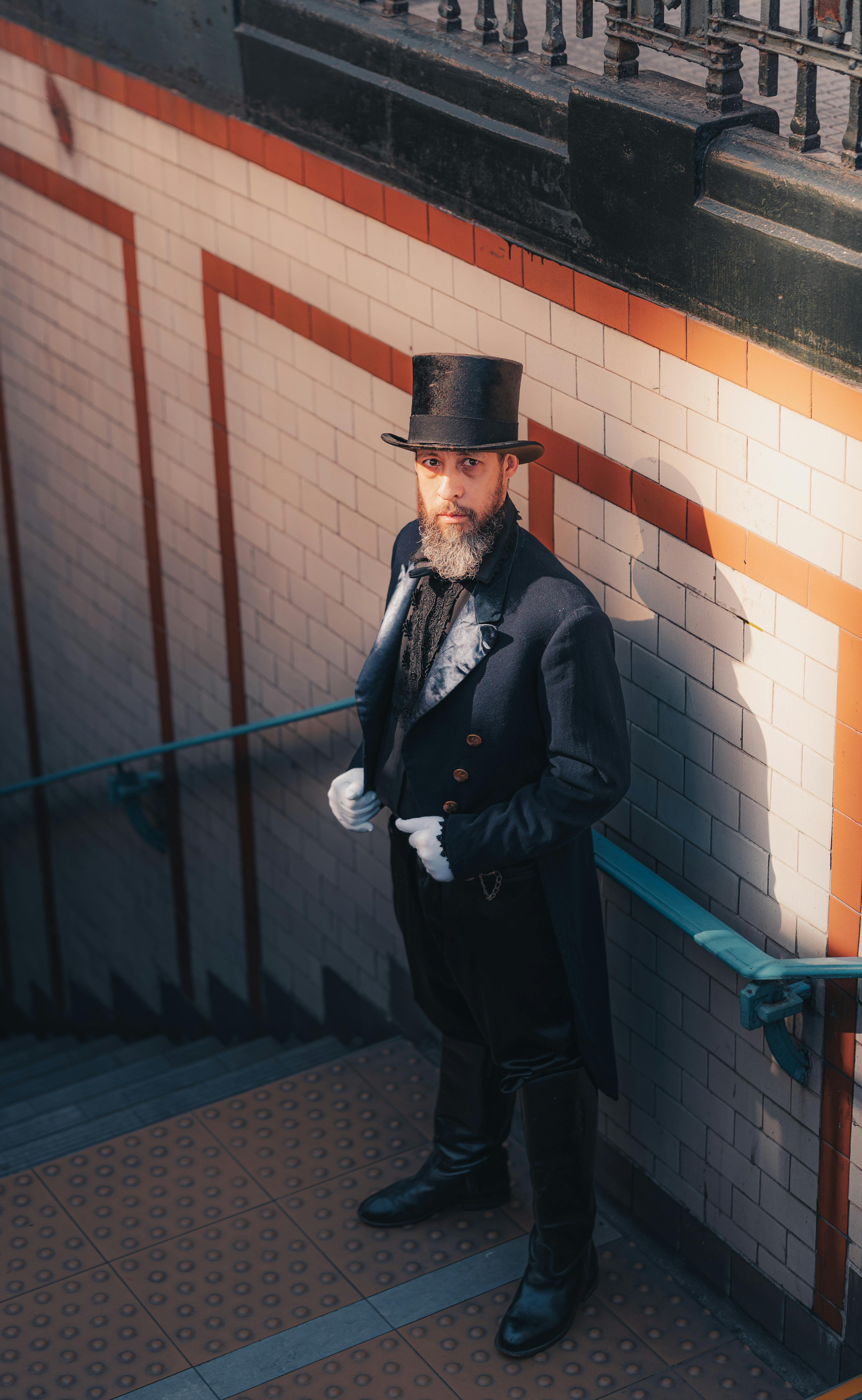 A man in Victorian attire descends subway stairs, casting a dramatic shadow.