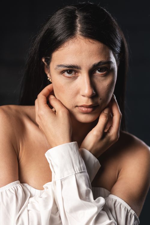 Free A striking portrait of a woman with expressive eyes, wearing an off-shoulder white blouse. Stock Photo