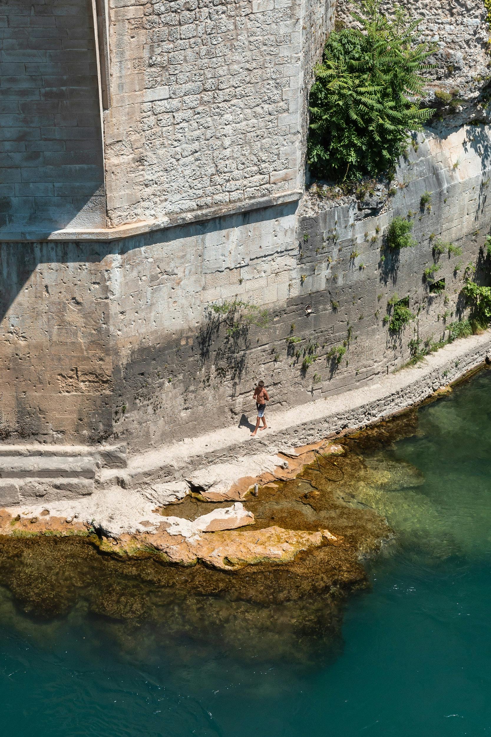 View of a person walking beneath the old bridge in Mostar, Bosnia and Herzegovina.
