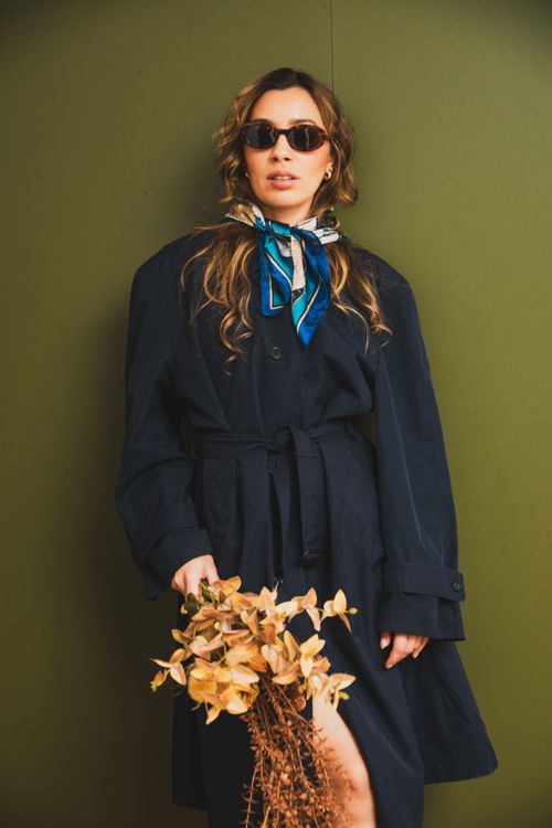 Free Stylish woman poses with sunglasses and dried flowers against a green background. Stock Photo