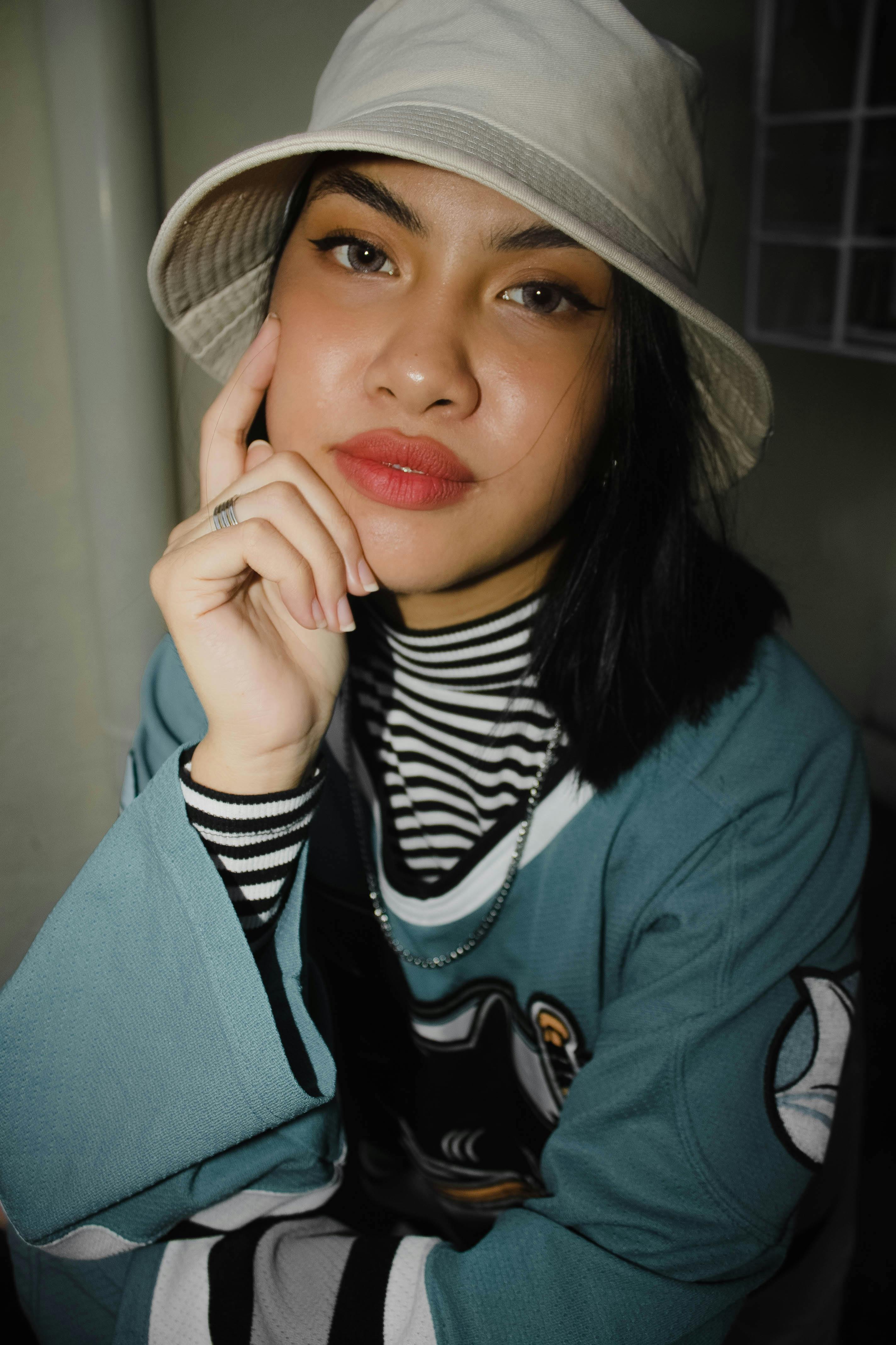 一位时尚女士头戴水桶帽，身穿运动服，在室内自信地摆着姿势