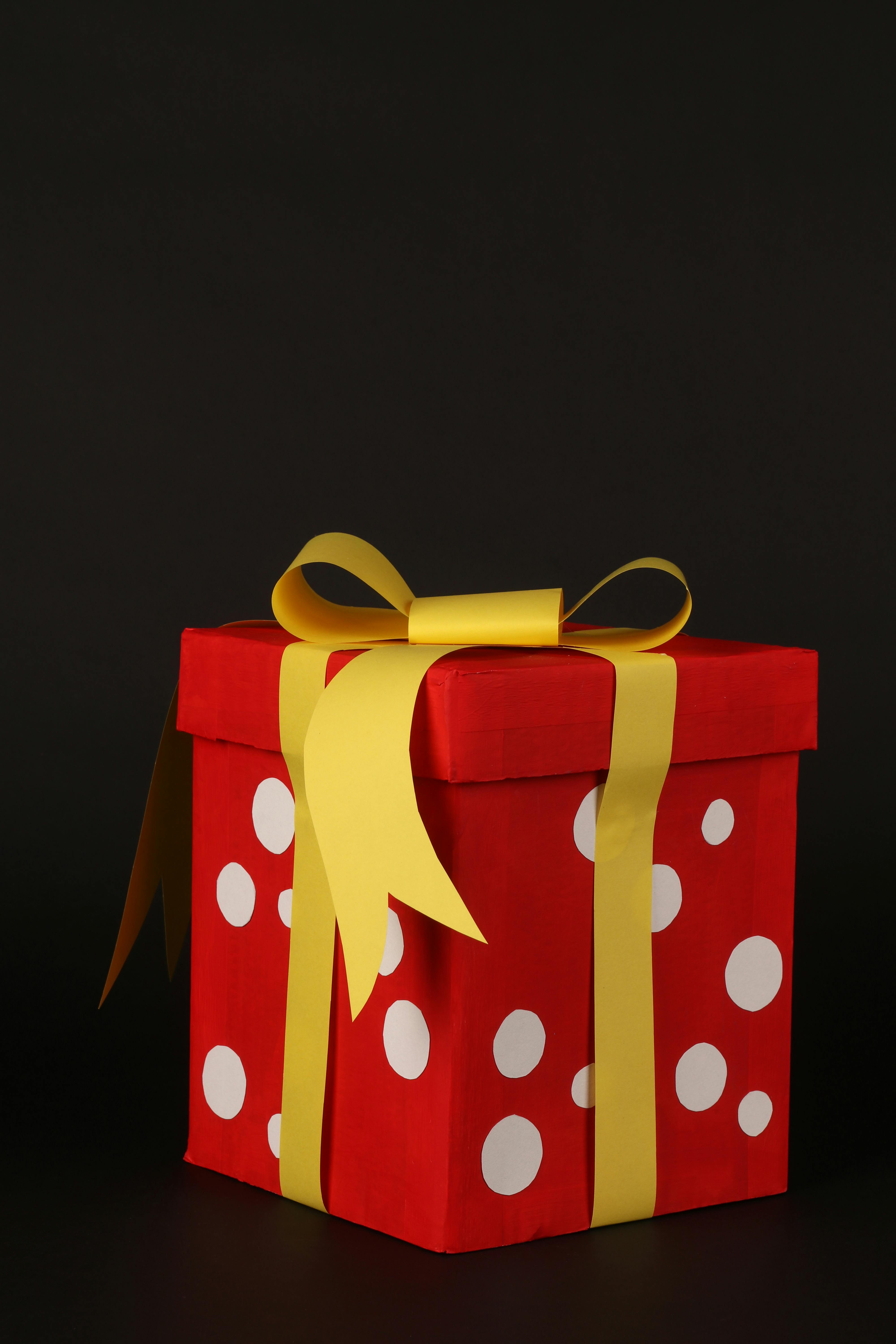 Gratis Kotak hadiah merah meriah dengan motif polkadot putih dan pita kuning, cocok untuk perayaan. Foto Stok