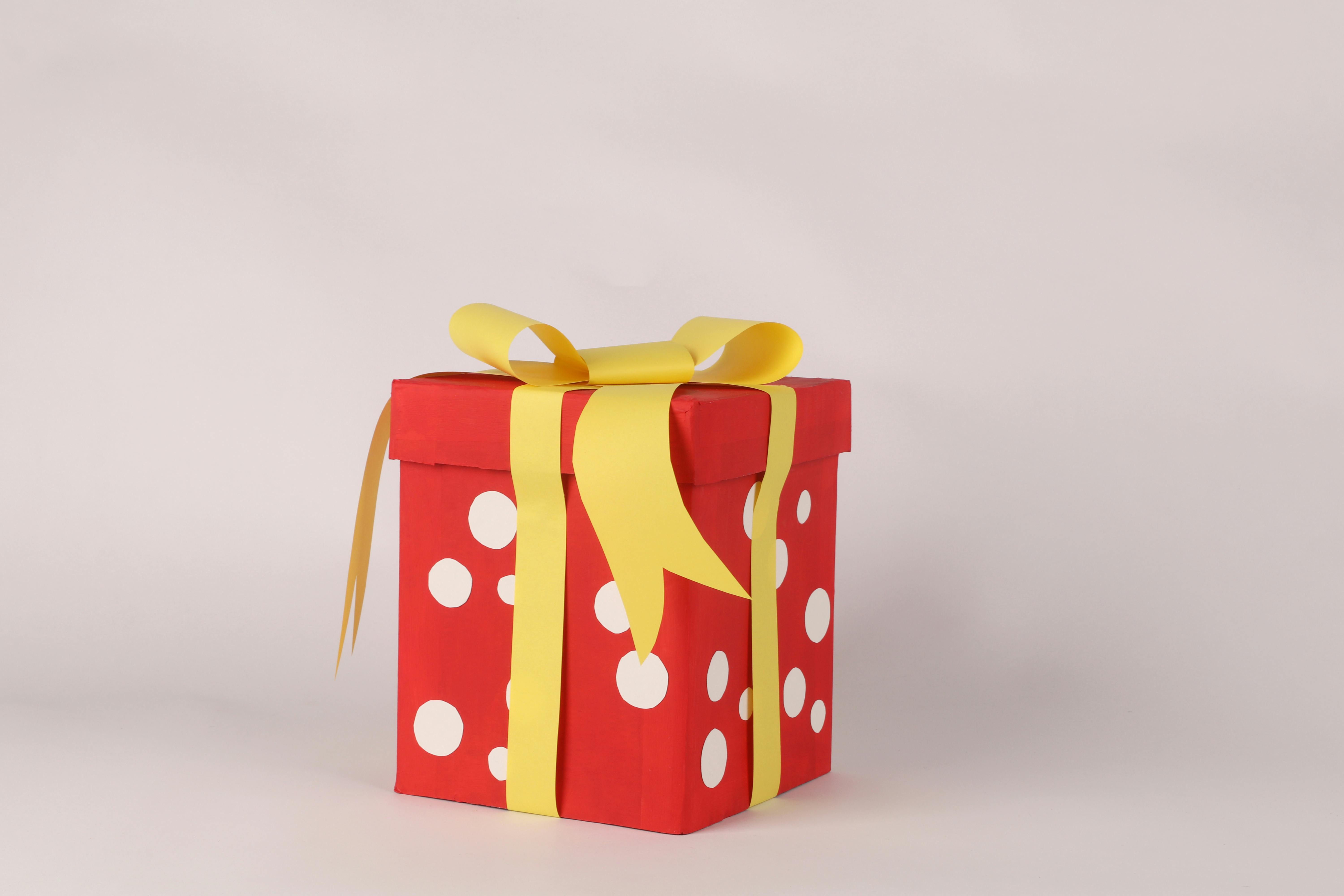 grátis Uma caixa de presente vermelha com bolinhas brancas e uma fita amarela, perfeita para comemorações. Foto profissional