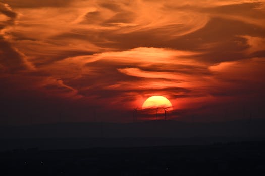 A breathtaking sunset in İstanbul with wind turbines silhouetted against vibrant clouds.