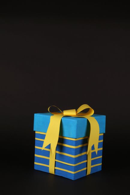 Beautifully wrapped blue gift box with yellow ribbon on dark backdrop for celebrations.