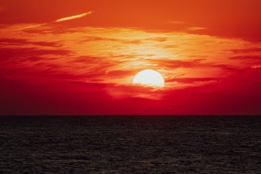 Breathtaking view of the sun setting over the ocean with a vivid red sky.