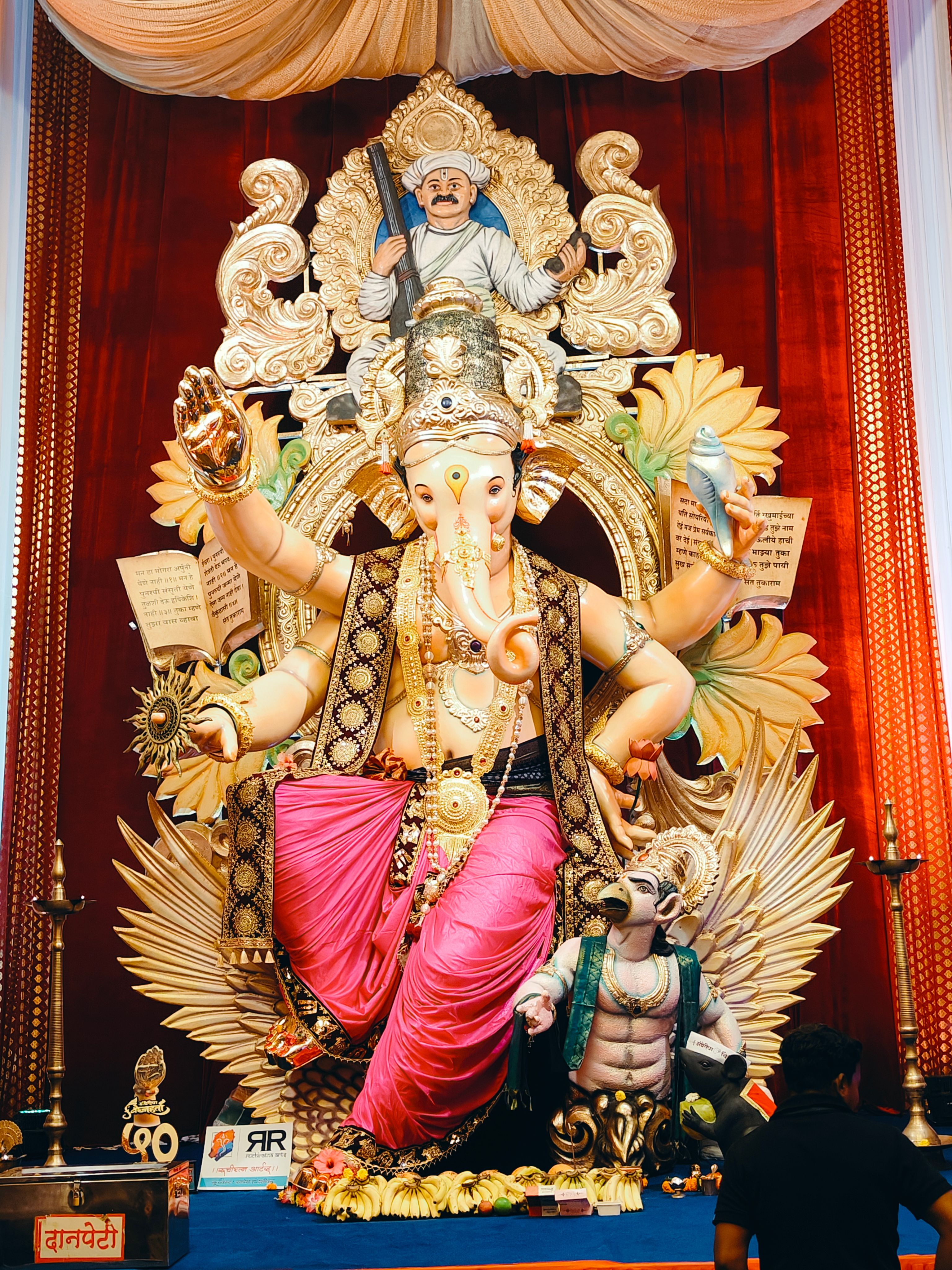 Colorful Ganesha idol with detailed decorations and vibrant backdrop.