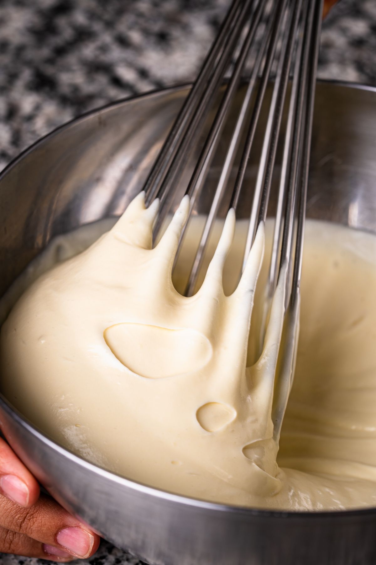 Creamy waffle batter being whisked in a metal mixing bowl