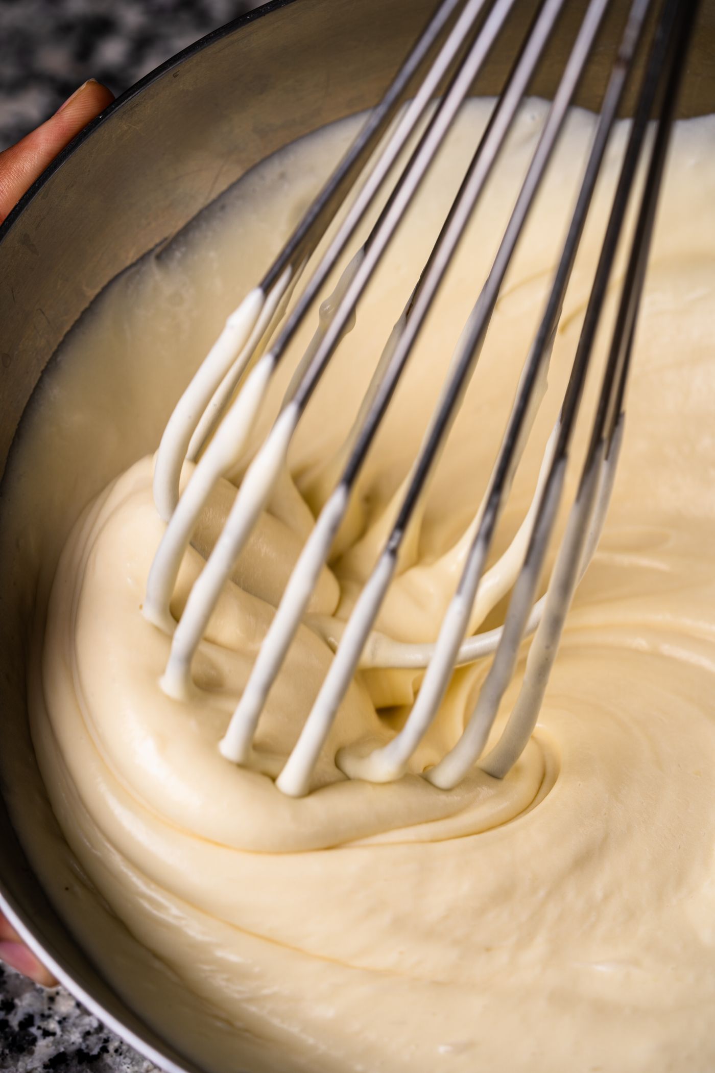 Fresh creamy pancake batter being mixed with a whisk in a bowl