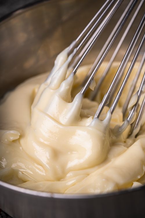 Free Close-up of creamy custard being whisked, showcasing its smooth texture and rich color. Stock Photo