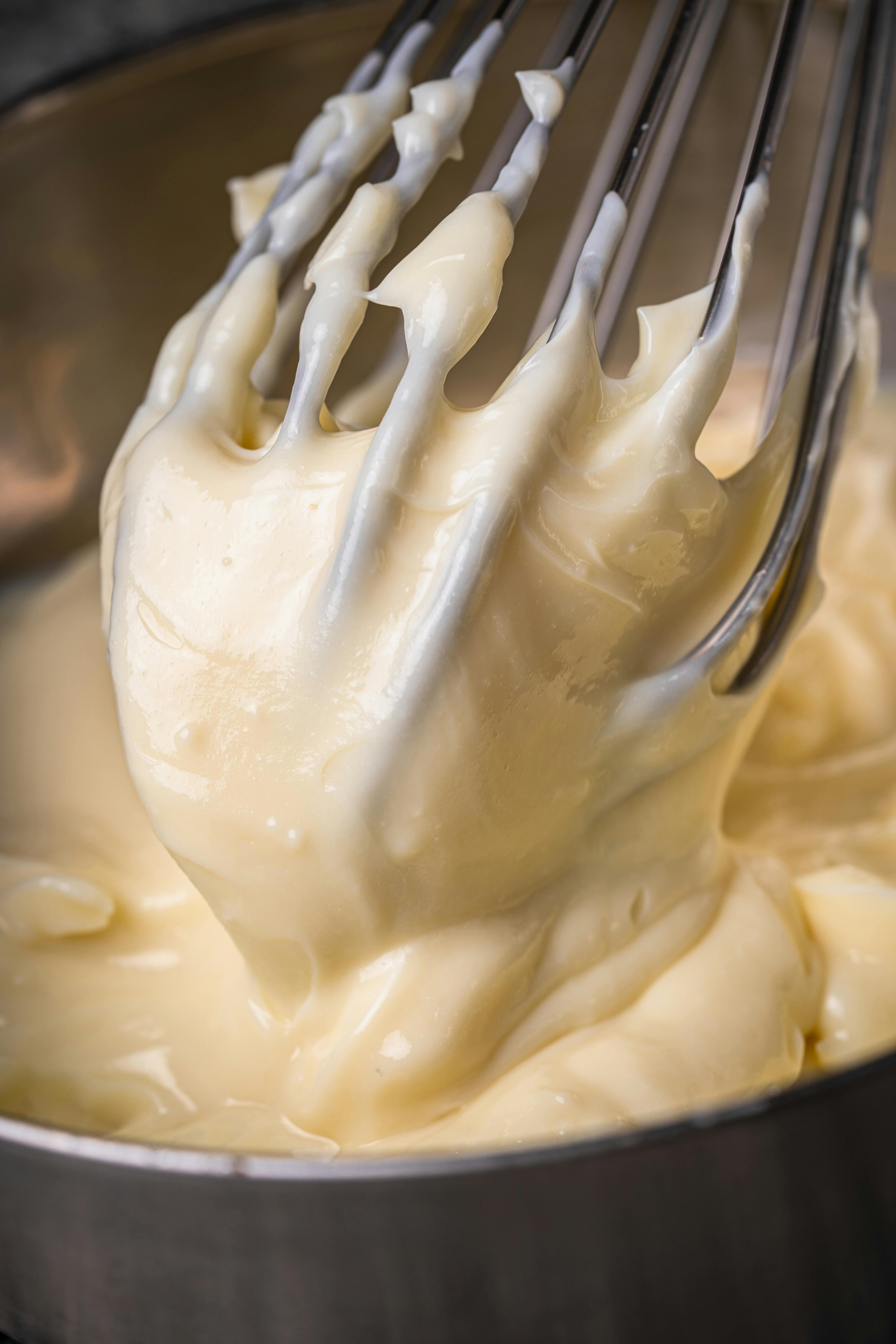 Primo piano di pastella cremosa mescolata con frusta in ciotola