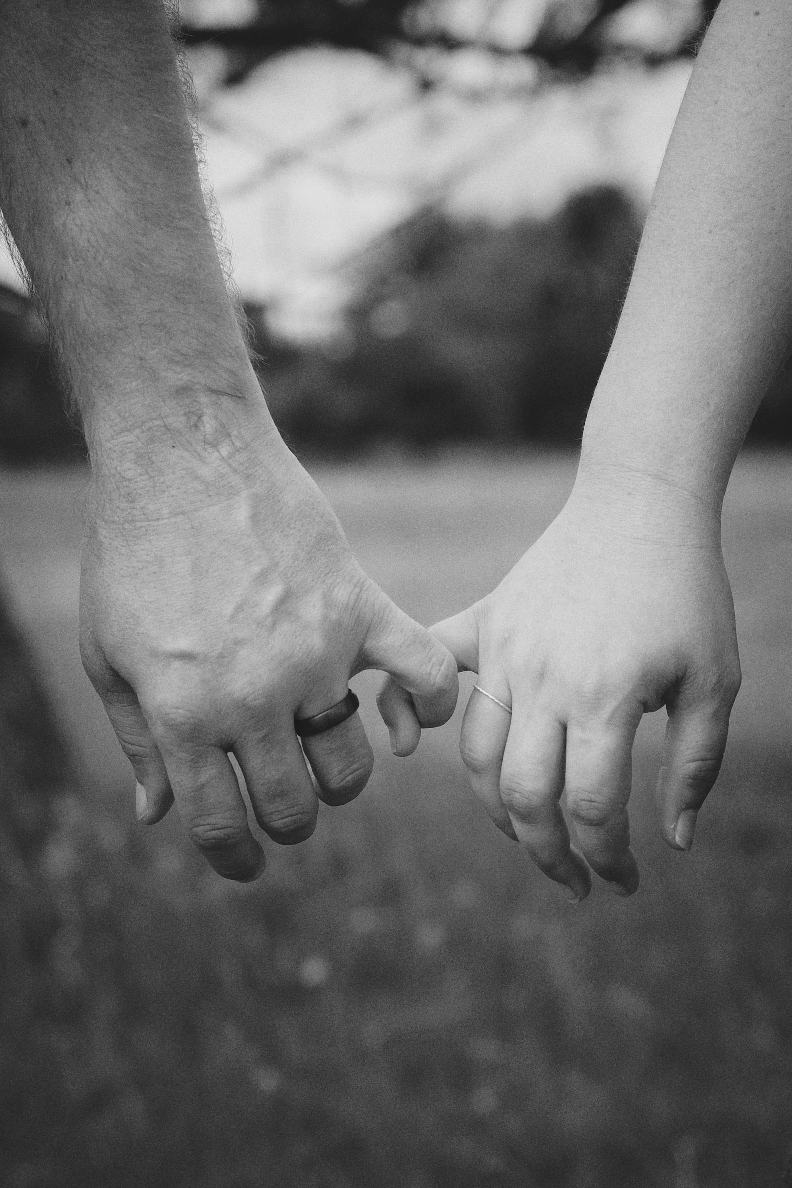 A close-up of two people holding hands outdoors