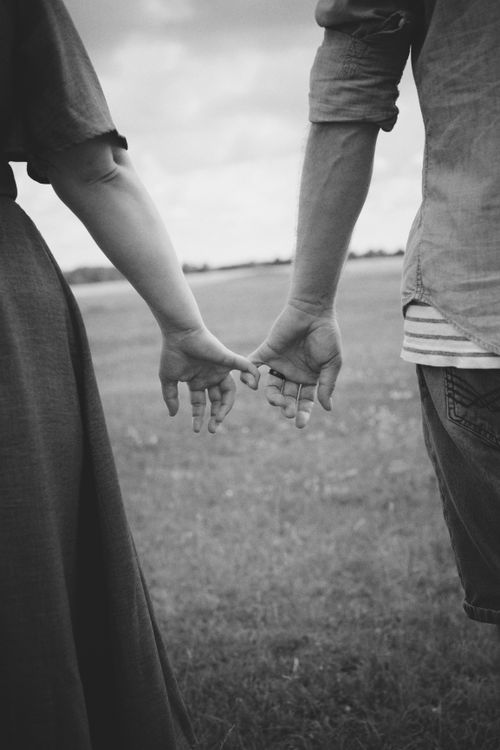 Free Black and white photo of a couple holding hands in a field, evoking romance and simplicity. Stock Photo
