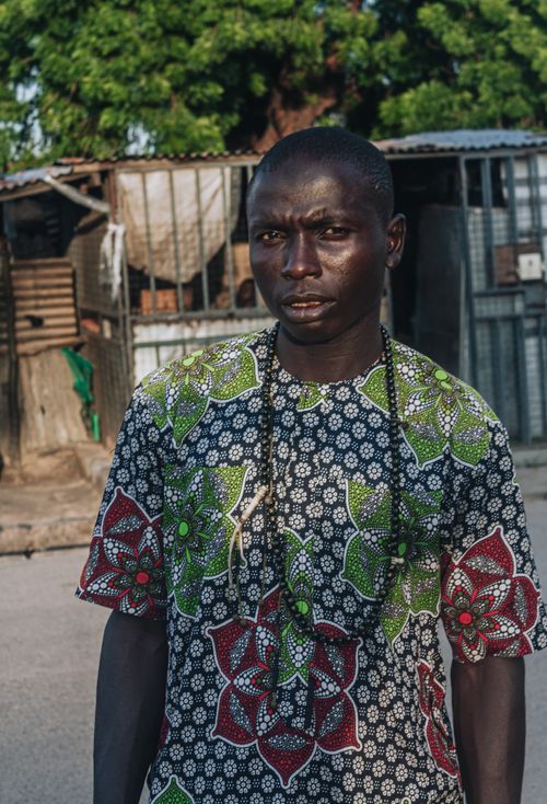 Free Portrait of a man wearing a colorful African pattern shirt against a rustic background. Natural lighting enhances the mood. Stock Photo