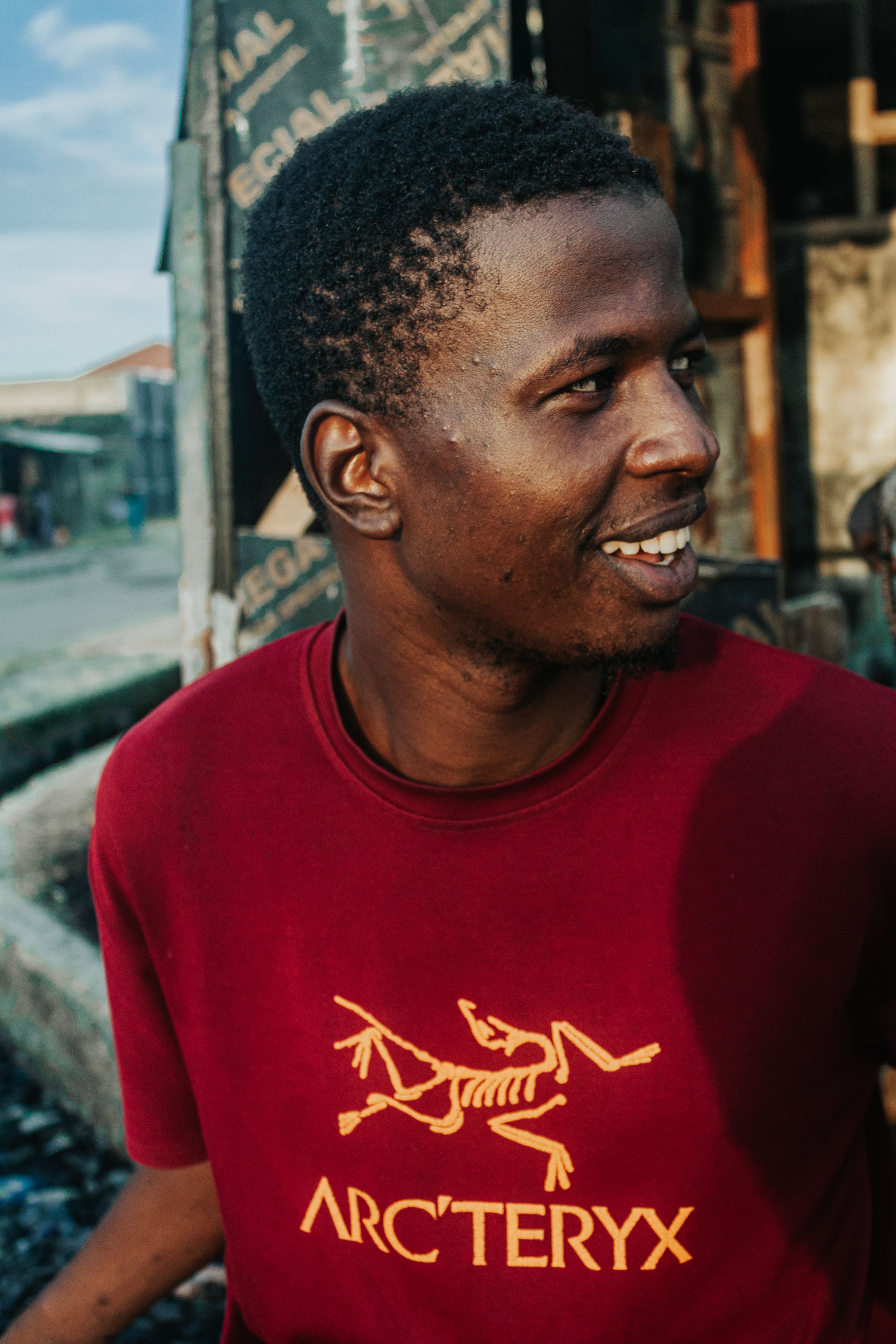 Smiling man wearing a red graphic t-shirt in an outdoor urban environment.