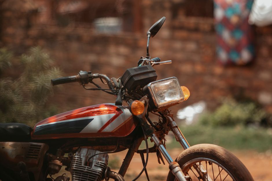 Close-up of a vintage motorcycle parked in a rustic outdoor setting.