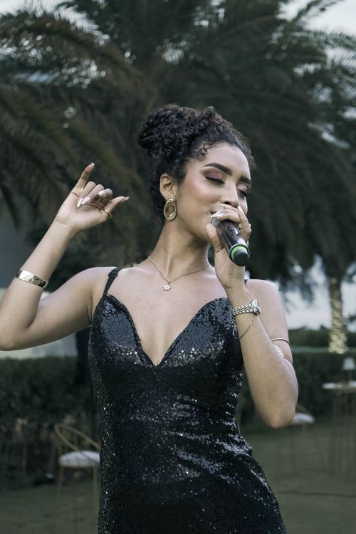Free A stylish female singer passionately performing outdoors with a microphone. Stock Photo