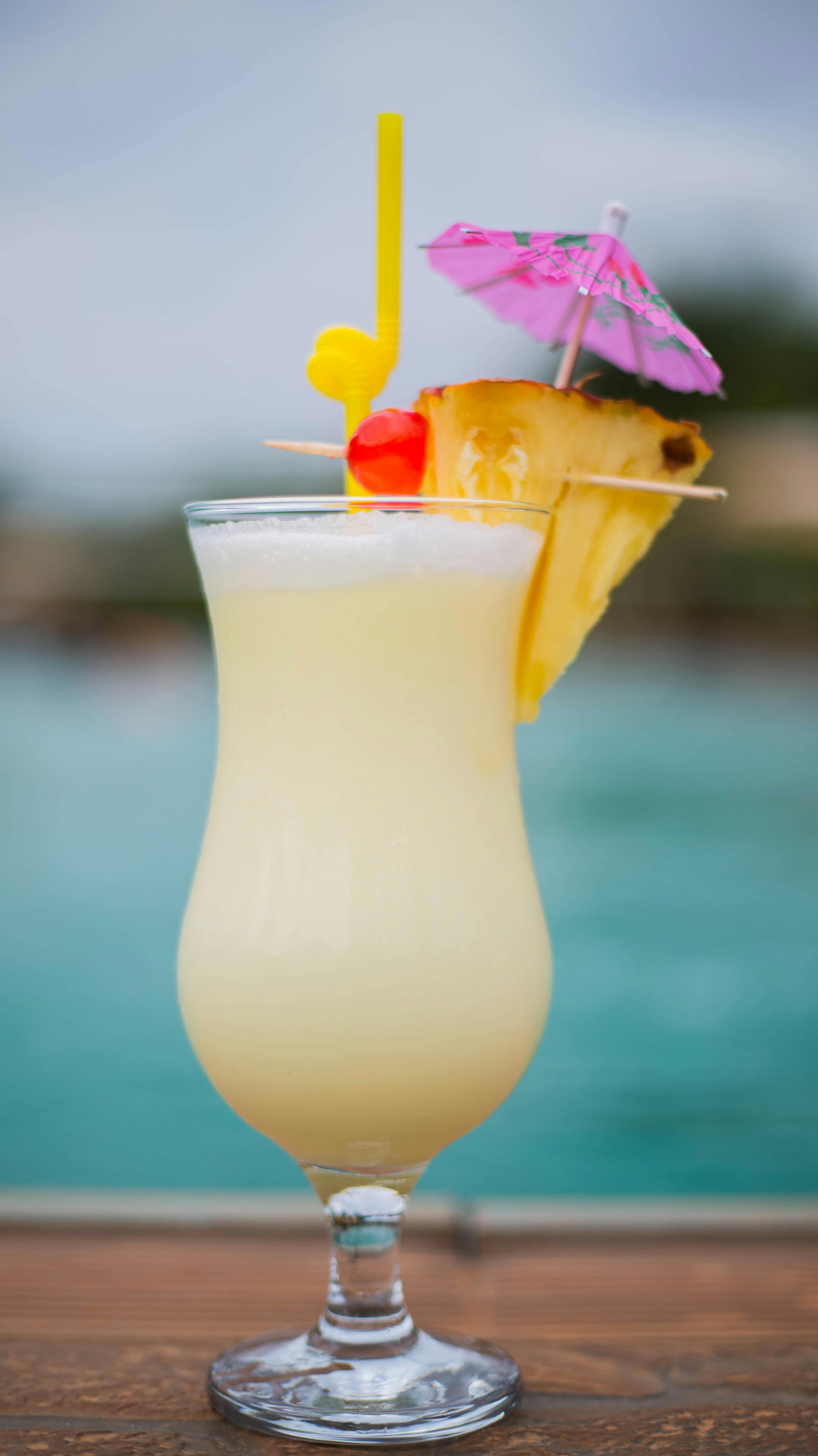 Free A delicious piña colada with pineapple and cherry garnish by the pool. Stock Photo