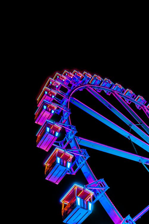 Free A stunning Ferris wheel lit with colorful neon lights against a dark night sky. Stock Photo