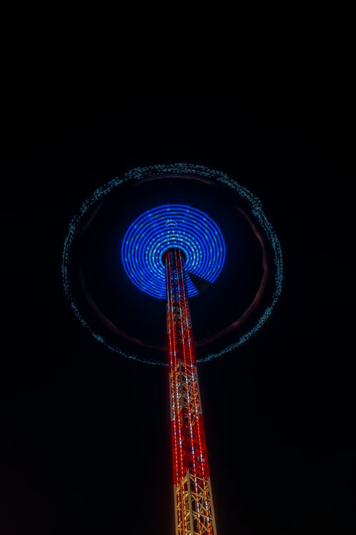 Free Colorful amusement park ride with light trails at night, creating vivid patterns in the dark sky. Stock Photo