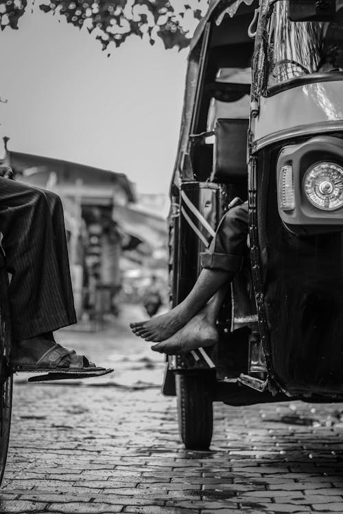 Grayscale Photography of Person Sitting Inside Tuk-tuk
