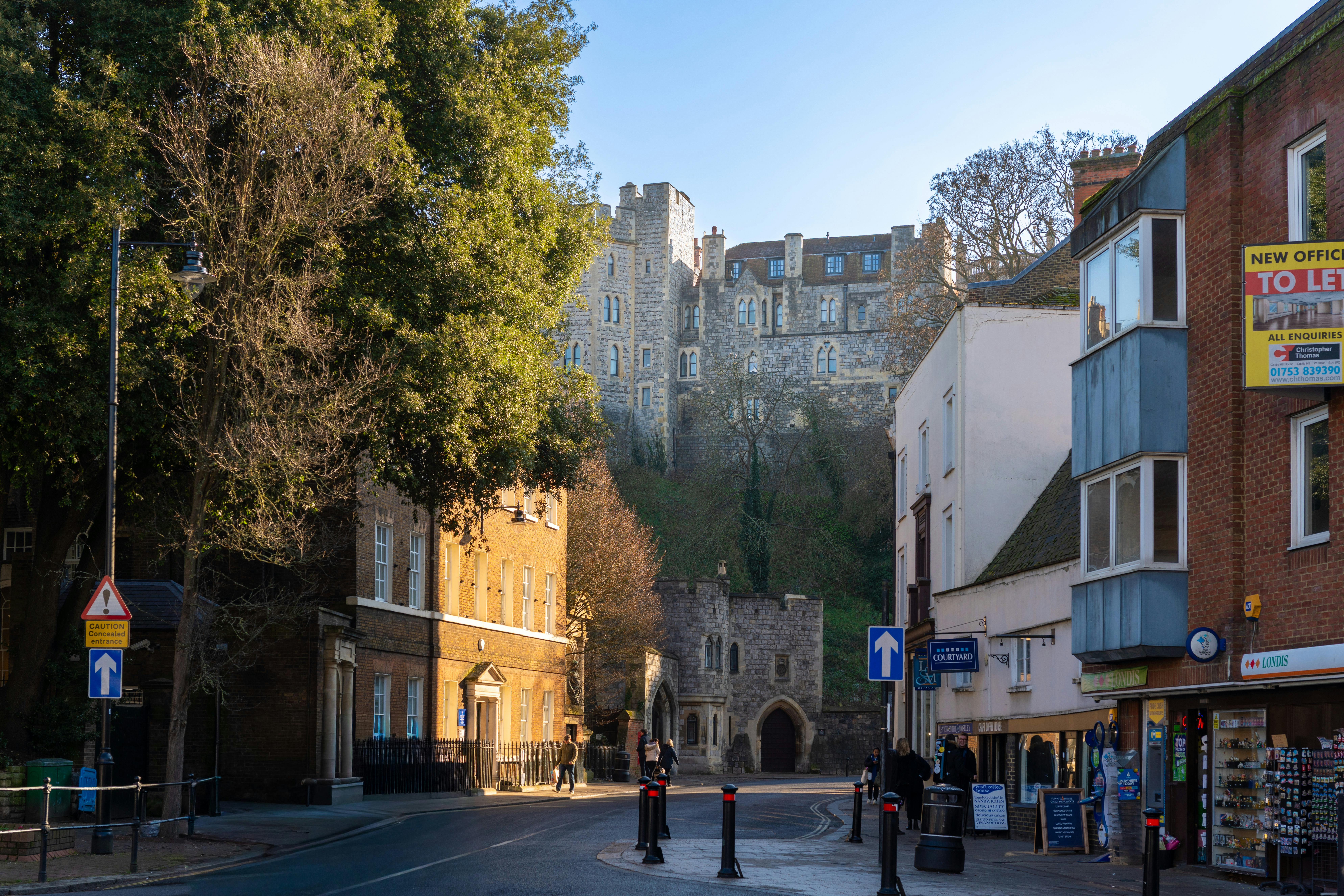 Charming street view of Windsor with Windsor Castle towering in the background on a sunny day.