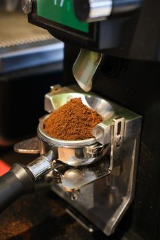 Espresso machine grinding fresh coffee grounds for brewing in a portafilter.
