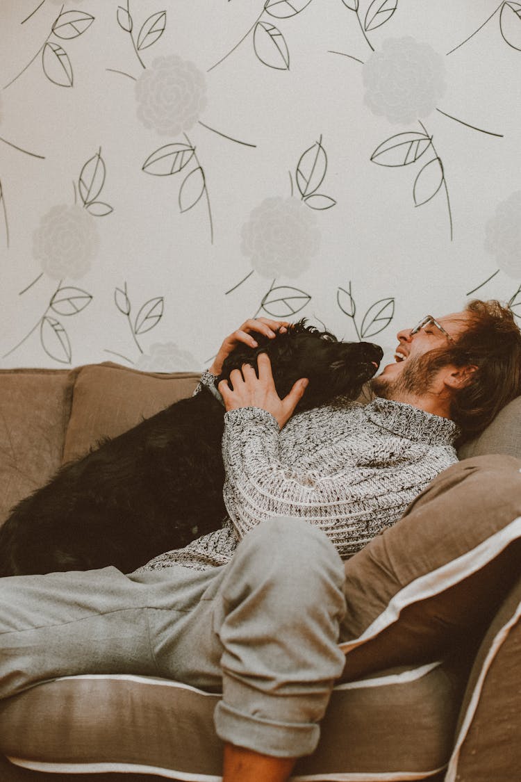 Man Sitting On The Sofa With His Black Dog