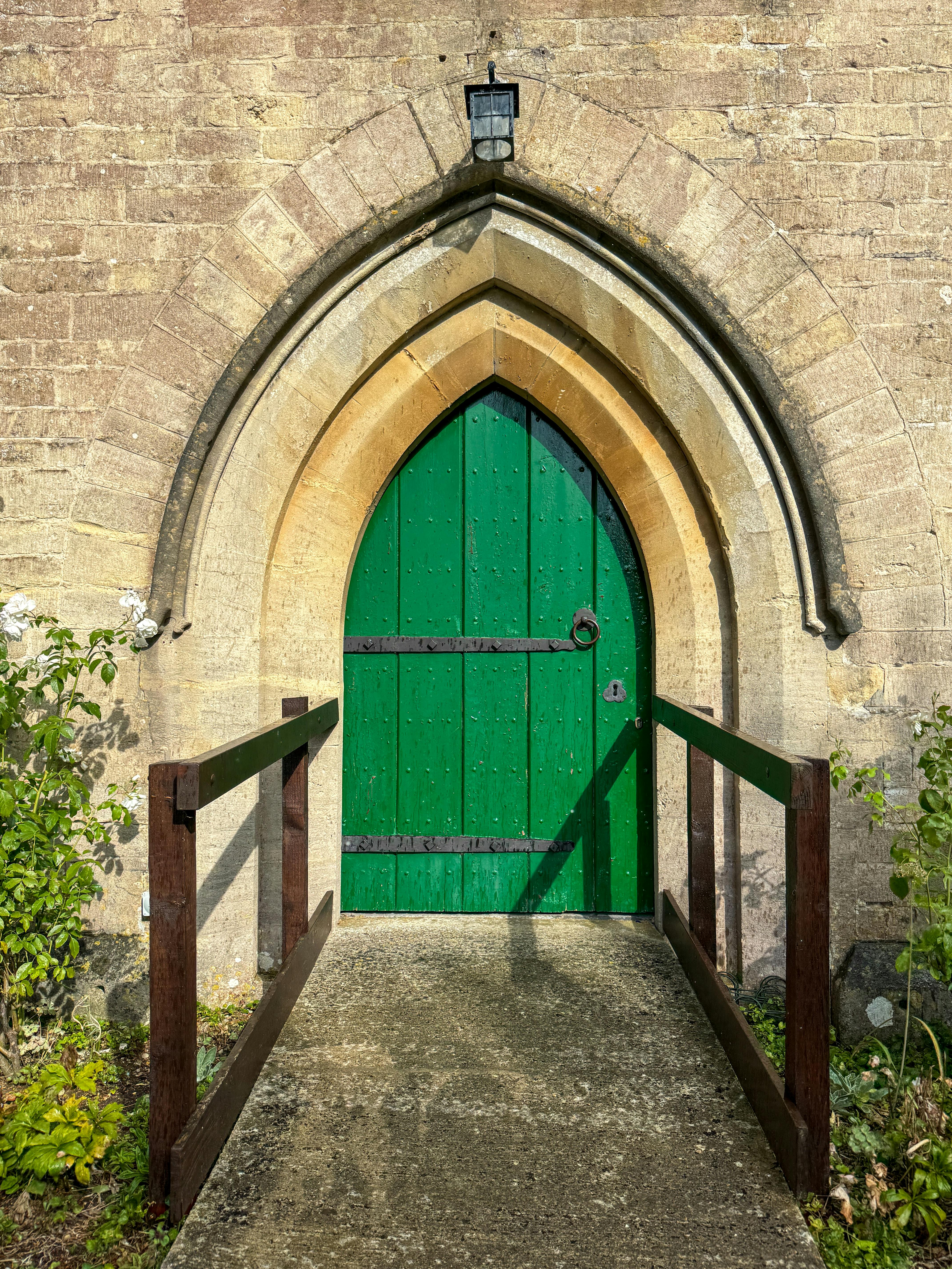 A striking green door set in a classic Gothic arch in Broad Town, England.