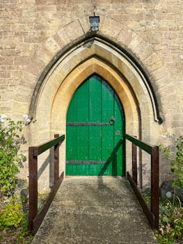 A striking green door set in a classic Gothic arch in Broad Town, England.