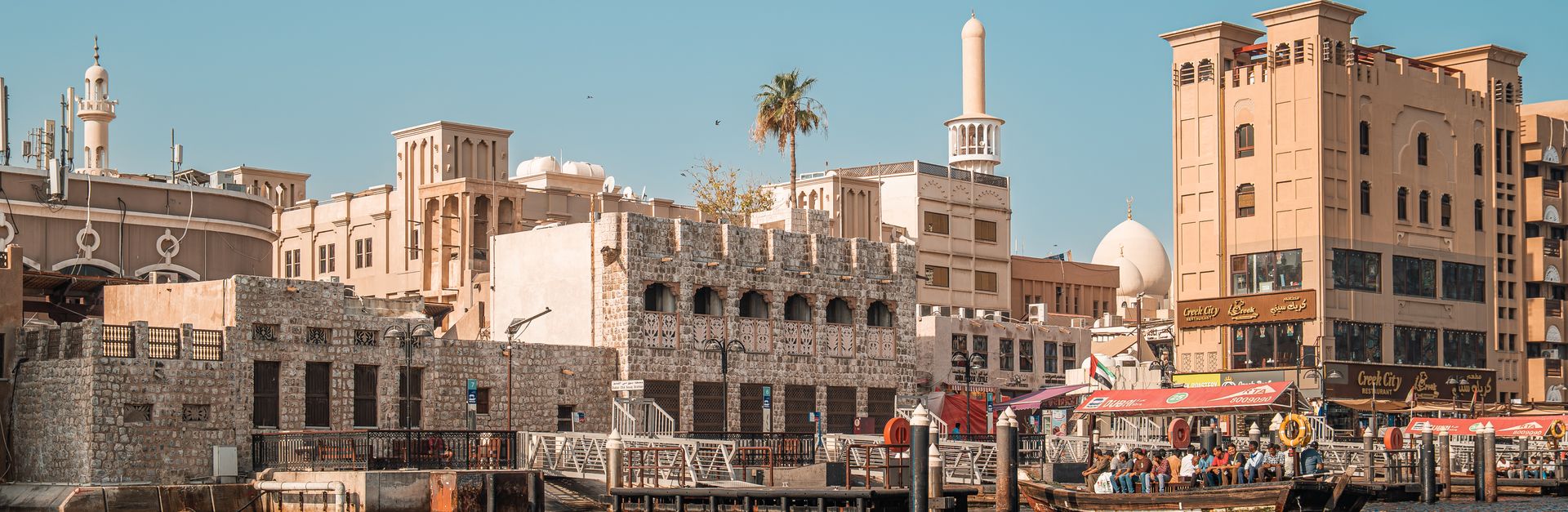 A picturesque view of traditional and modern buildings along Dubai Creek, showcasing Dubai's unique