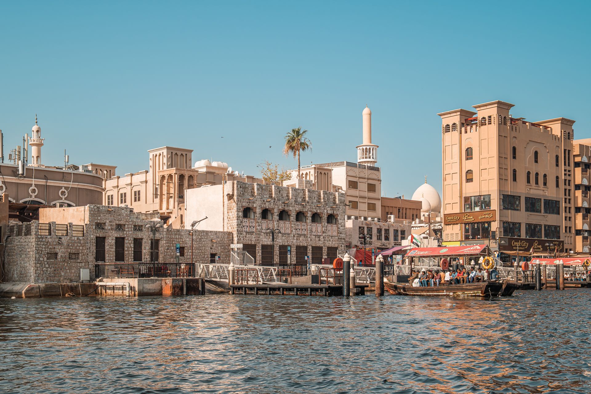 A picturesque view of traditional and modern buildings along Dubai Creek, showcasing Dubai's unique