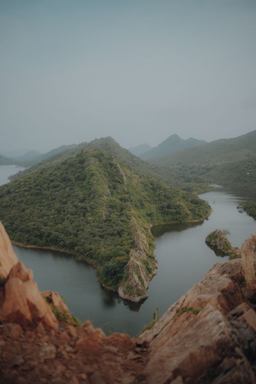 Free A stunning aerial view of a tranquil mountain lake surrounded by lush greenery and rocky hills. Stock Photo