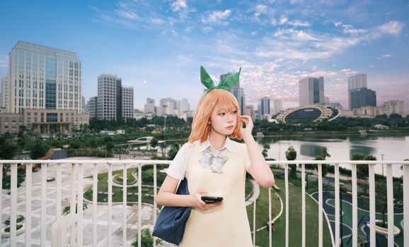 A cosplayer dressed as an anime character poses in a modern city park with a skyline backdrop.
