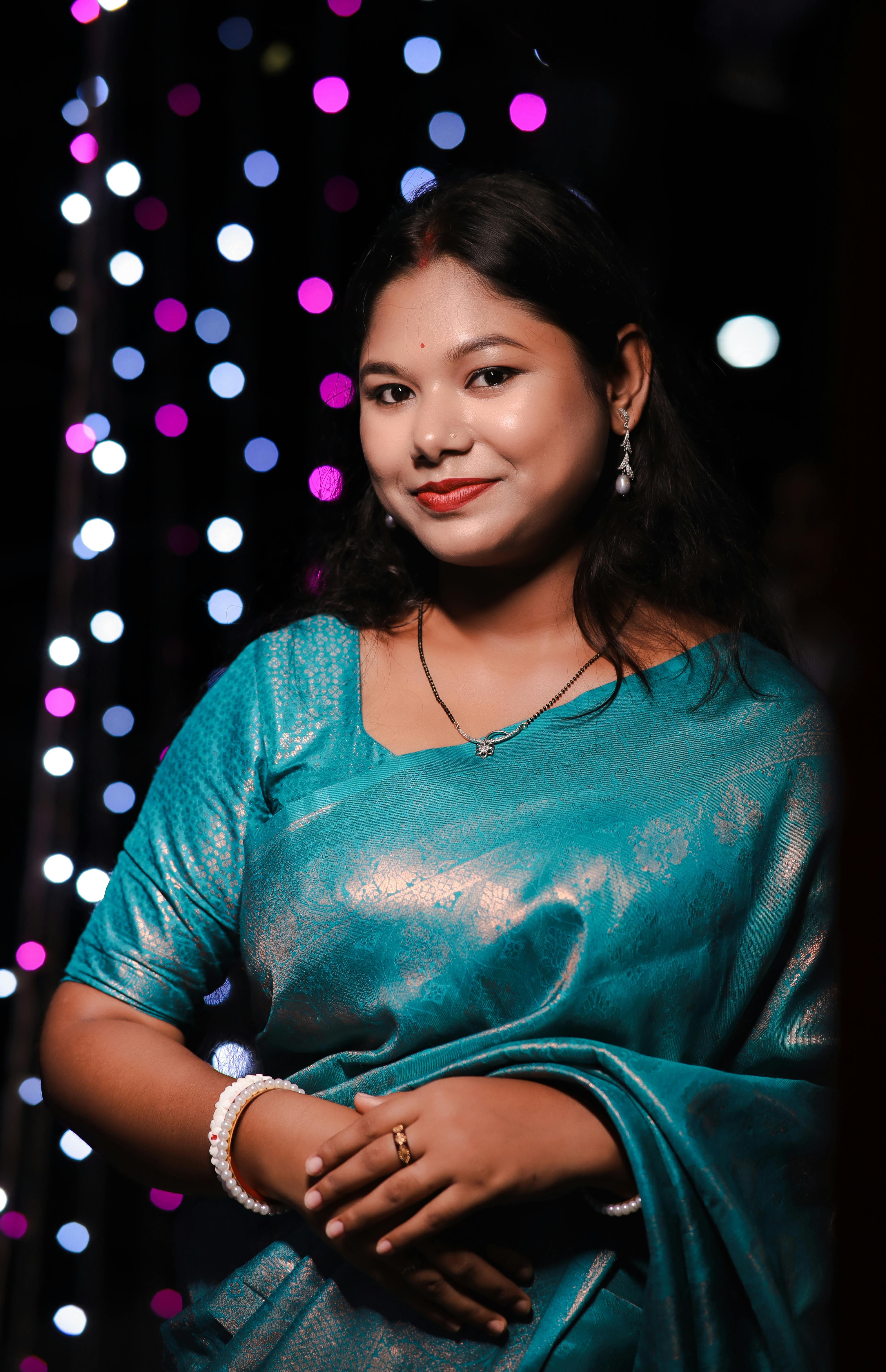Elegant portrait of a woman in beautiful teal traditional attire with festive lights.