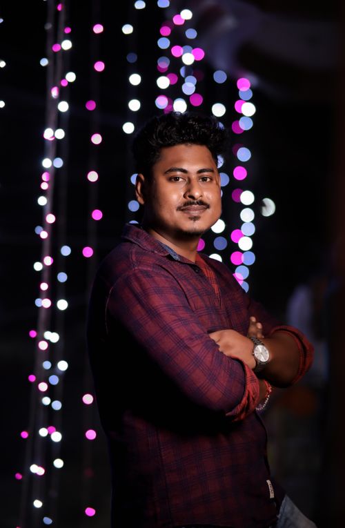 Free Confident young man posing with colorful bokeh lights in the background. Stock Photo